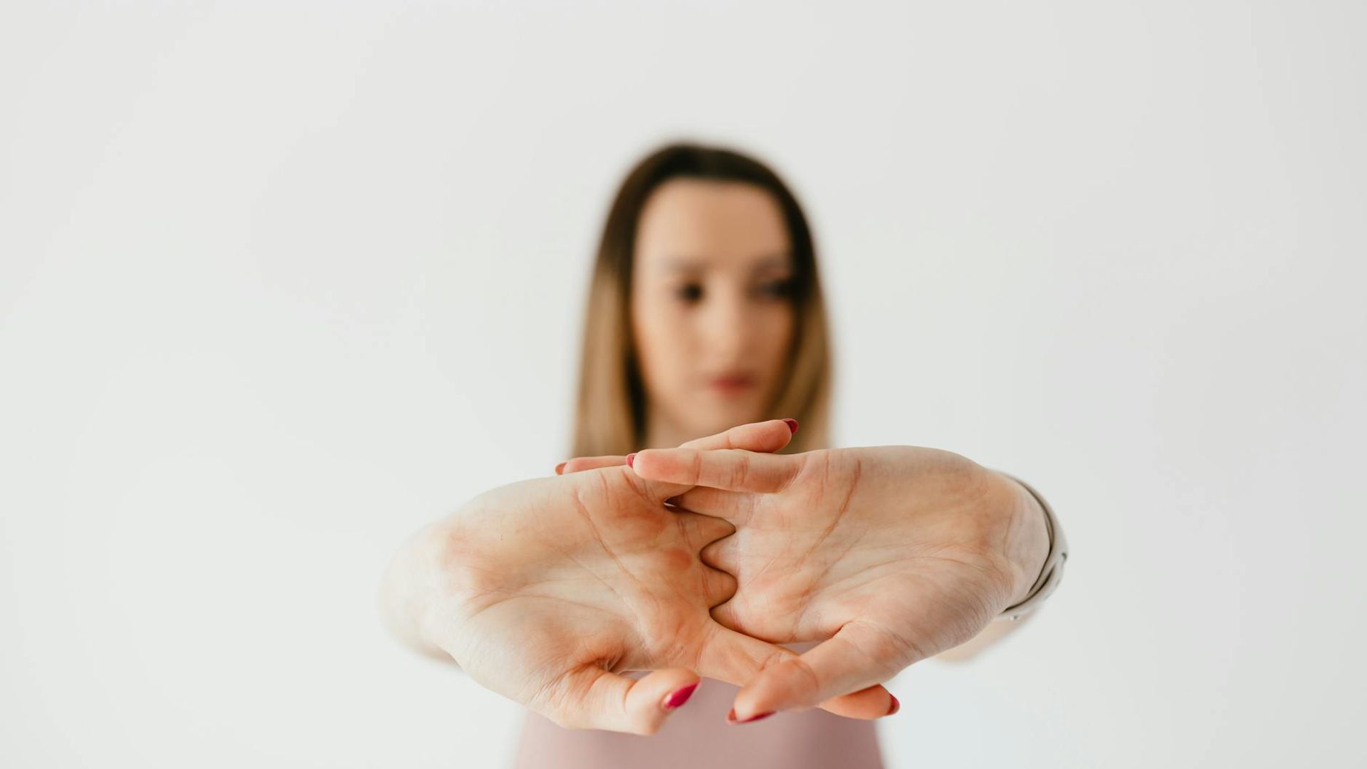 A serene woman practicing a gentle stretching pose in a calm, dark studio.